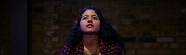 A person sits on stage looking off into the distance