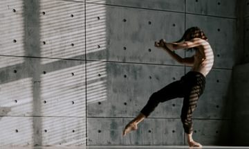 A dancer moves with a concrete background behind him