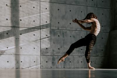 A dancer moves with a concrete background behind him