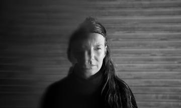 a black and white image of a women with long her. Half her face is blurred and she looks mysteriously to the side