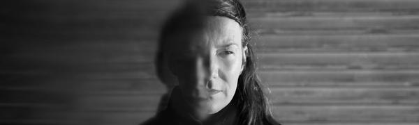 a black and white image of a women with long her. Half her face is blurred and she looks mysteriously to the side