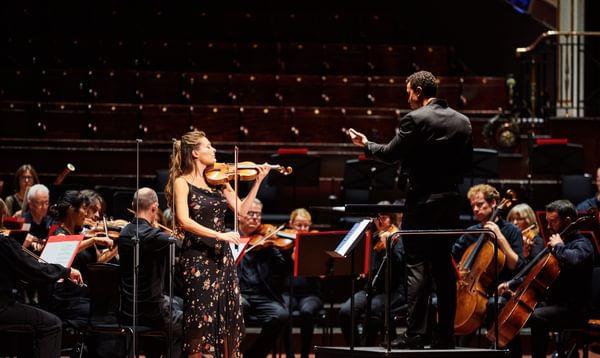 A woman stands on stage playing a violin