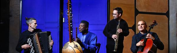 four men sit together holding instruments