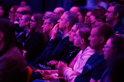 a group of people sit facing the stage, deep in thought