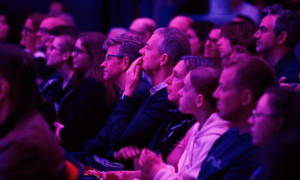 a group of people sit facing the stage, deep in thought