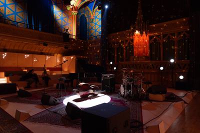 A dimly lit stage with instruments and a microphone set up ready for a performance