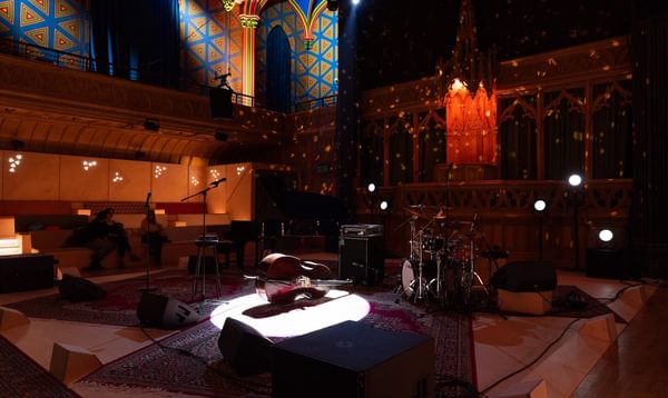 A dimly lit stage with instruments and a microphone set up ready for a performance