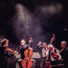 a group of five musicians have just finished playing and are posed dramatically