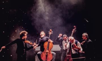 a group of five musicians have just finished playing and are posed dramatically
