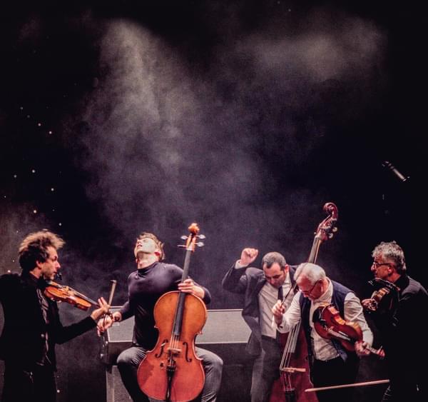 a group of five musicians have just finished playing and are posed dramatically