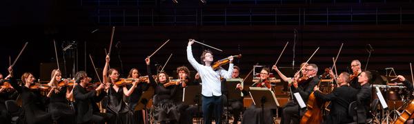 a group of string players flourish their bows in the air