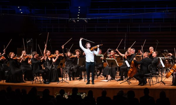 a group of string players flourish their bows in the air