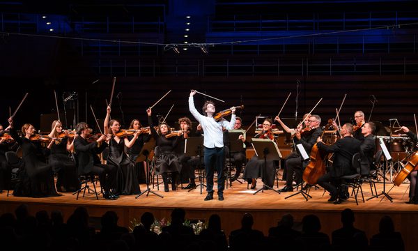 a group of string players flourish their bows in the air