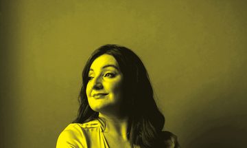 A black and yellow photo of Beth Taylor sitting down and looking away from the camera