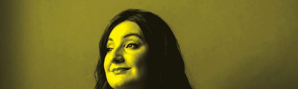 A black and yellow photo of Beth Taylor sitting down and looking away from the camera