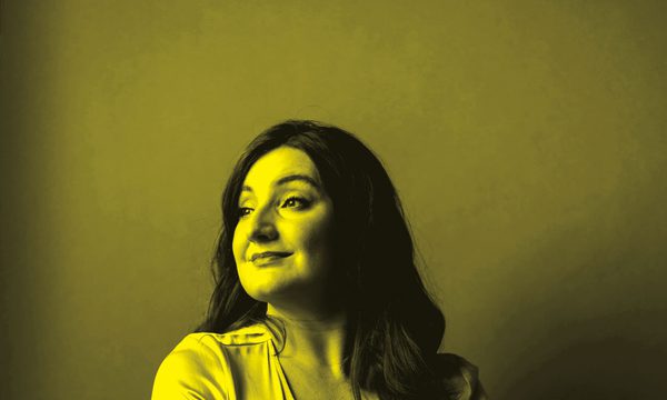 A black and yellow photo of Beth Taylor sitting down and looking away from the camera