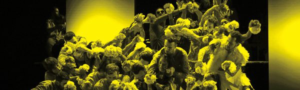 A black and yellow image of an ensemble of dancers moving across the stage