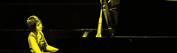A black and yellow image of Yuja Wang playing piano on stage