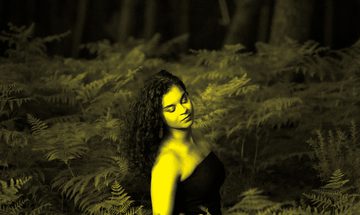 A black and yellow image of Julie Roset surrounded by leaves