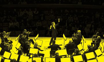 A black and yellow image of a conductor and an orchestra performing on stage