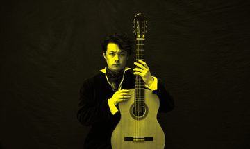 A black and yellow image of Sean Shibe holding a guitar and looking at the camera