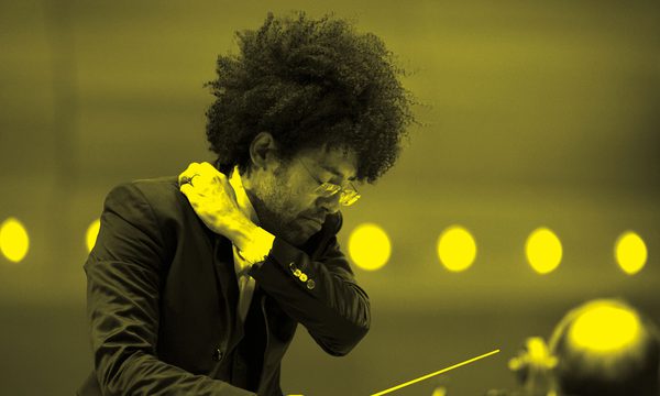 A black and yellow image of Rafael Payare conducting an orchestra while holding a baton and swinging his arm