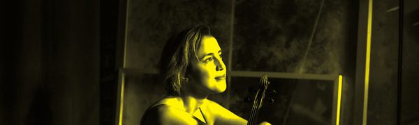 A black and yellow image of a woman sitting holding a violin while looking away from the camera
