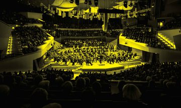 A black and yellow image of an orchestra performing on stage