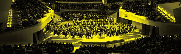 A black and yellow image of an orchestra performing on stage
