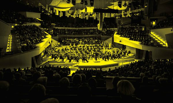 A black and yellow image of an orchestra performing on stage
