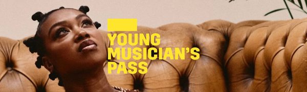 A yellow Young Musician's Pass logo in front of a woman sitting on the floor holding a saxophone and looking upwards