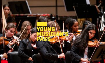 A yellow Young Musician's Pass logo in front of an ensemble of strings players from National Youth Orchestra of the United States of America