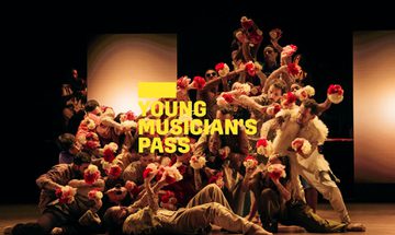 A yellow Young Musician's Pass logo in front of a large ensemble of dancers move as one while tightly packed together and holding white and red flowers