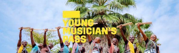 A yellow Young Musician's Pass logo in front of a group of women with vibrantly coloured hair stand in a row holding up drumsticks