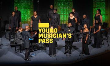 A yellow Young Musician's Pass logo in front of a group of people singing on stage holding microphones