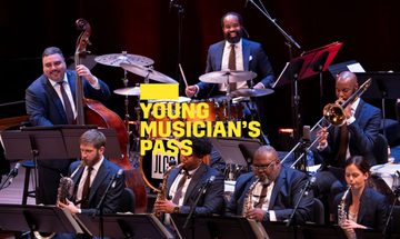A yellow Young Musician's Pass logo in front of players from Jazz at Lincoln Center performing on stage