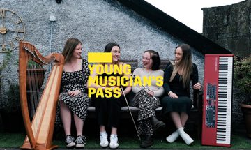 A yellow Young Musician's Pass logo in front of four women sit on a bench outside with their instruments, clarsach, fiddle, whistle and keyboard