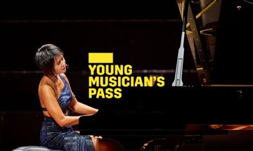 A yellow Young Musician's Pass logo in front of a woman wearing a blue dress playing a piano on stage
