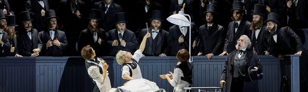 An early 20th century surgeon operates on someone in the middle of a crowded theatre. He holds up a piece of viscera in tongs to the shock of onlookers.