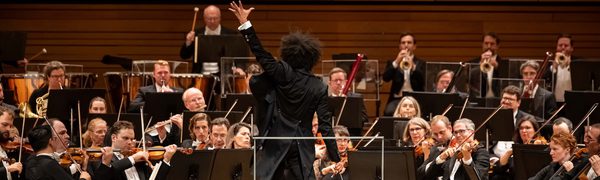 An image of a conductor and an orchestra performing on stage