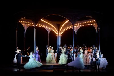 An image of performers dressed in ballgowns and suits dancing under a pavilion