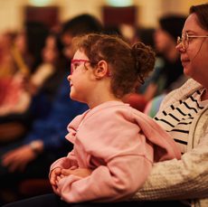 a girl sits on her mothers lap focused on something in the distance
