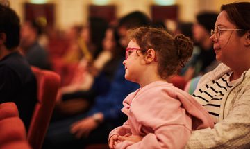 a girl sits on her mothers lap focused on something in the distance
