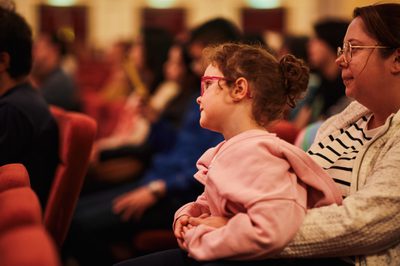 a girl sits on her mothers lap focused on something in the distance