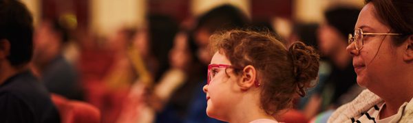 a girl sits on her mothers lap focused on something in the distance