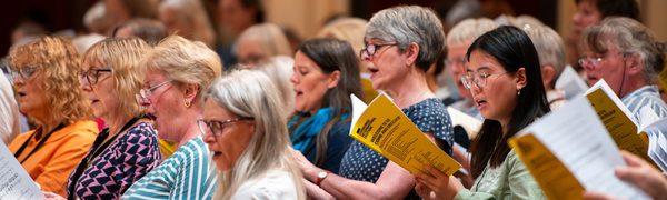 A group of people singing from books of sheet music