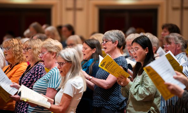 A group of people singing from books of sheet music