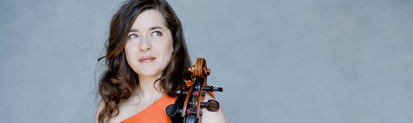 A woman wearing an orange dress resting her hands on a cello