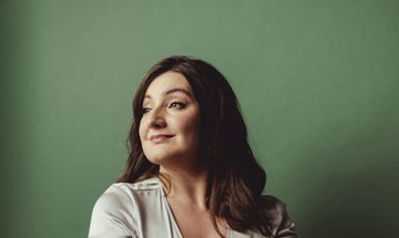 A woman wearing an off white dress smiling into the distance