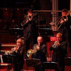 a group of brass musicians stand on stage